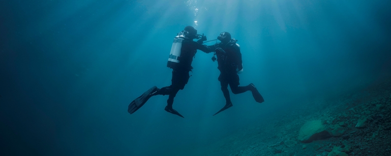 Under vatten: en dykare hjälper en annan dykare som har problem med lufttillförseln.