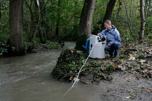 En kvinna övervakar vattenkvaliteten av en å i en skog