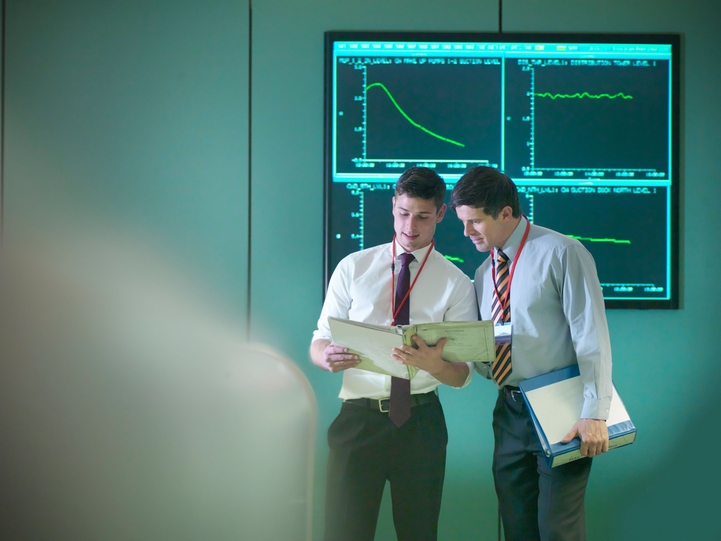 Two men stood in front of a screen looking at a folder