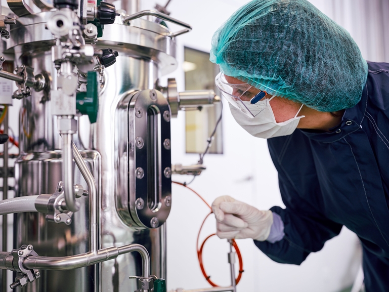 En forskare med en fermentor för biofarmaceutisk tillverkning i läkemedelsbranschen En fermentor och en forskare i biofarmaceutisk tillverkning