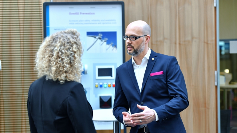 Medarbetare och kund i samtal framför en monter på ett seminarium