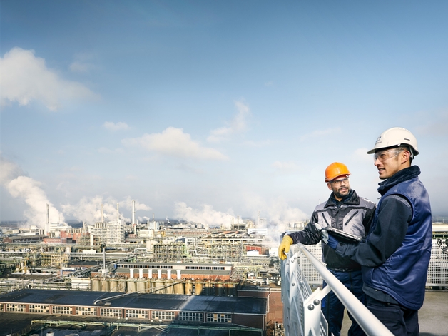 Två ingenjörer tittar på en stor industrianläggning.